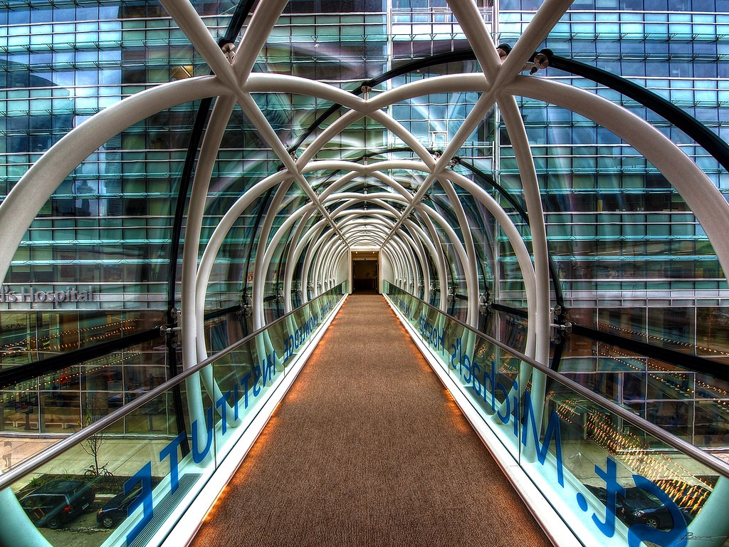 Modern glass and steel pedestrian bridge connecting medical facilities